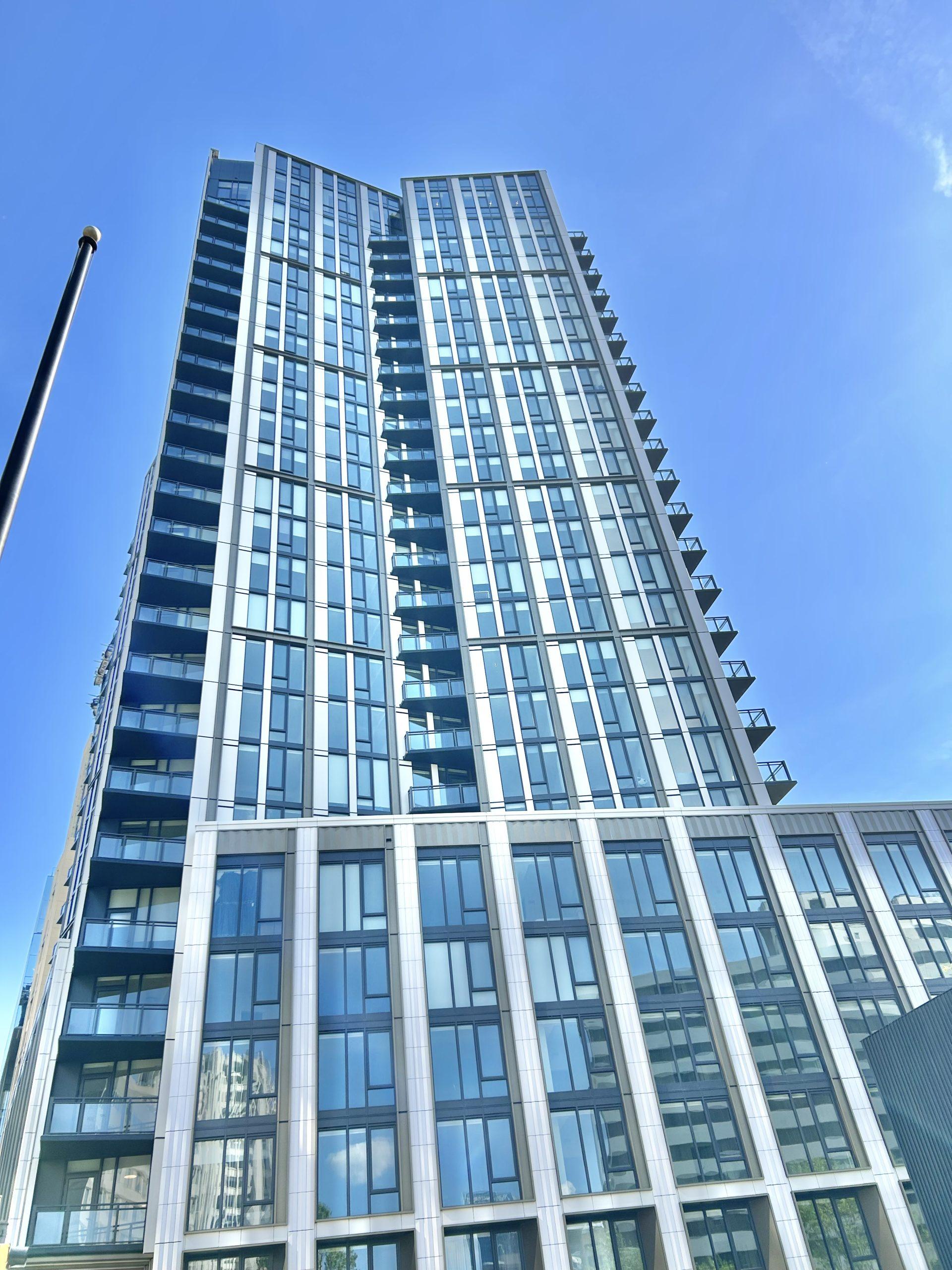 Residential tower rising above a city street under a clear blue sky